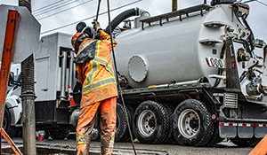 Worker using pump truck on sewer