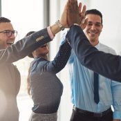 Happy successful multiracial business team giving a high fives gesture as they laugh and cheer their success